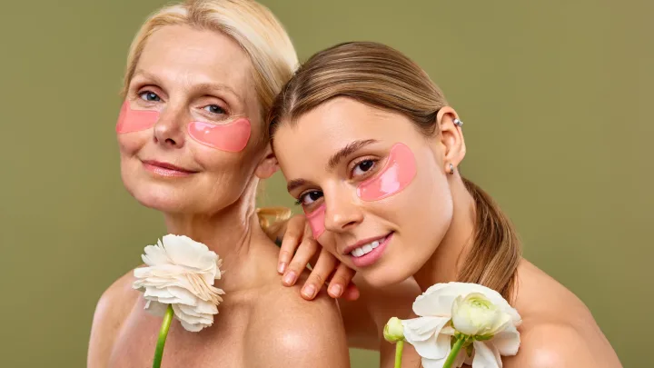 Women young and mature join together in a shared self-care routine, using under-eye patches to moisturize and white flowers to relax during their wellness routine. Cosmetology, skin care, spa.